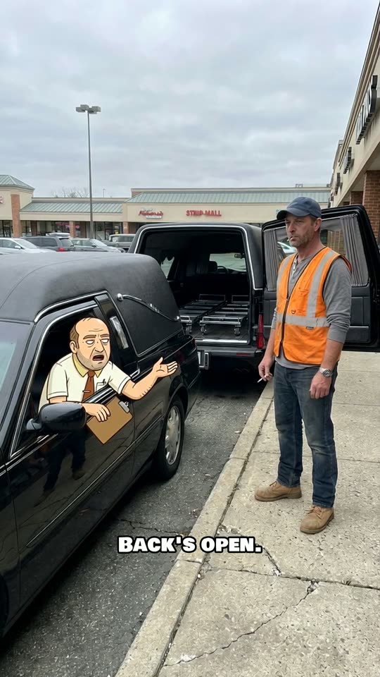 The Clerk leaning out of a hearse window talking to a man in an orange vest
